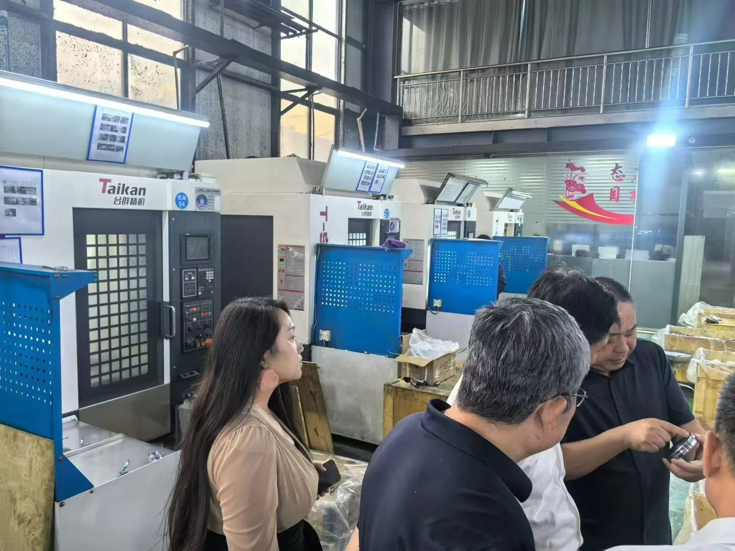 Fotografía de una visita al taller con visitantes junto a equipos de mecanizado CNC